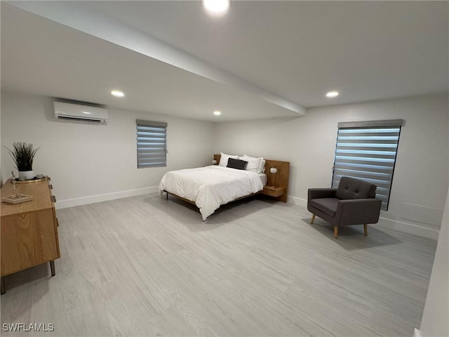 bedroom with a wall unit AC and light hardwood / wood-style floors