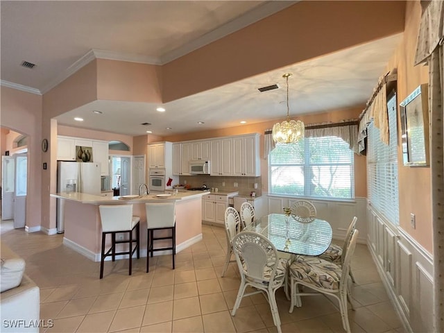 tiled dining space featuring an inviting chandelier and crown molding