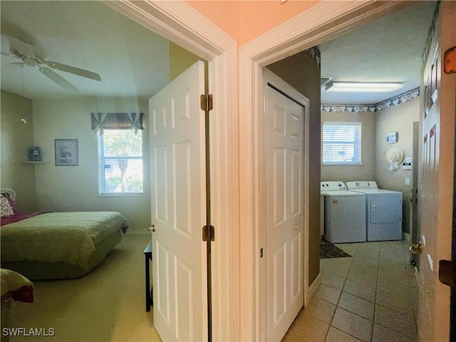 hallway with separate washer and dryer and light tile patterned floors