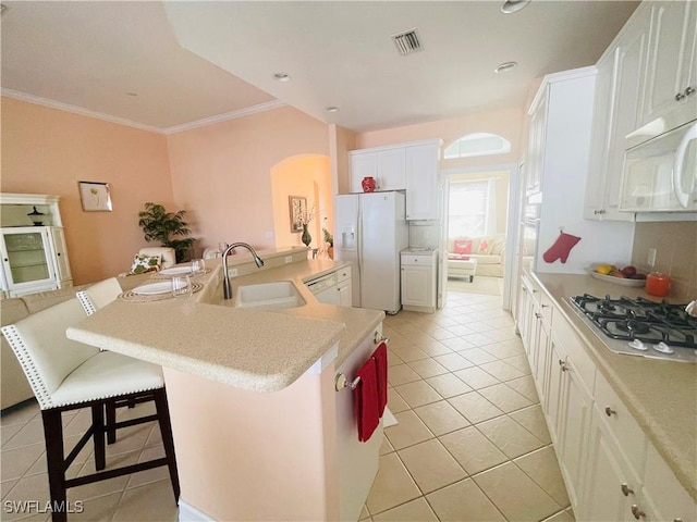 kitchen featuring white appliances, a breakfast bar, ornamental molding, white cabinets, and light tile patterned flooring