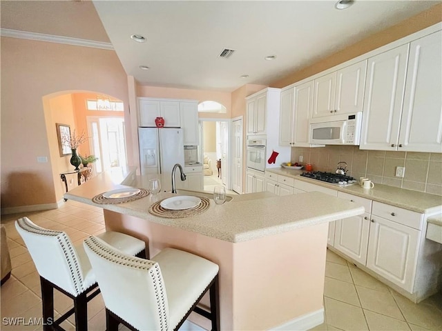 kitchen featuring white cabinetry, a center island with sink, white appliances, and light tile patterned floors