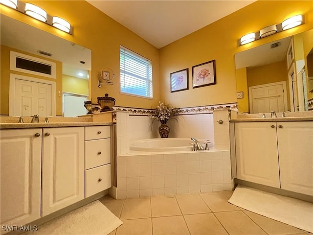 bathroom featuring tile patterned flooring, vanity, and tiled bath