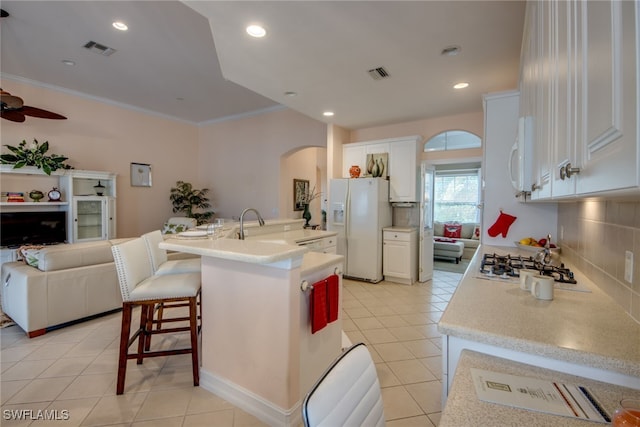 kitchen with white appliances, visible vents, white cabinets, an island with sink, and open floor plan