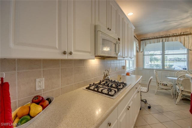 kitchen featuring white cabinetry, light countertops, gas cooktop, and white microwave