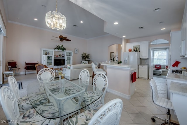 dining room featuring light tile patterned floors, visible vents, arched walkways, a ceiling fan, and crown molding