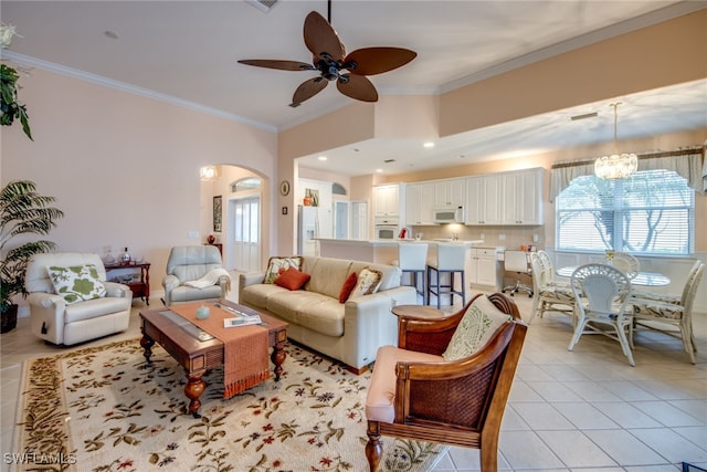 living area featuring arched walkways, light tile patterned flooring, crown molding, and ceiling fan with notable chandelier