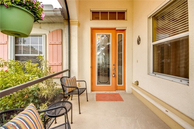 entrance to property featuring a balcony and stucco siding