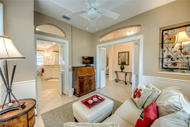 living room featuring light tile patterned floors, visible vents, a ceiling fan, and wainscoting