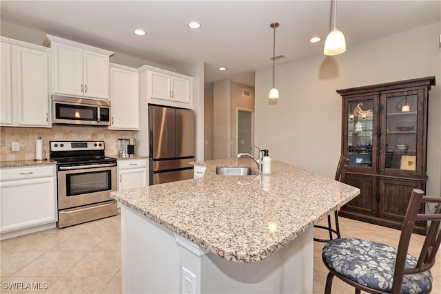 kitchen featuring an island with sink, stainless steel appliances, sink, and hanging light fixtures