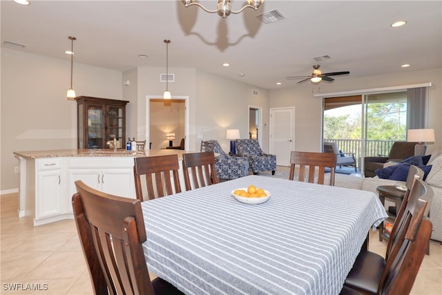 tiled dining space with sink and ceiling fan with notable chandelier