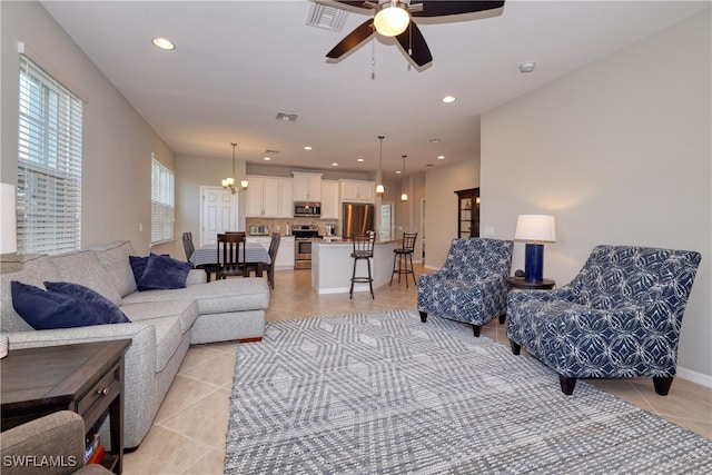 living room featuring light tile patterned flooring and ceiling fan with notable chandelier