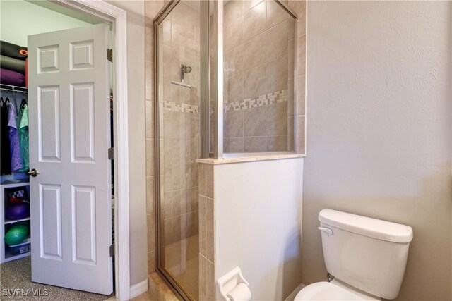 bathroom with a shower with door and toilet