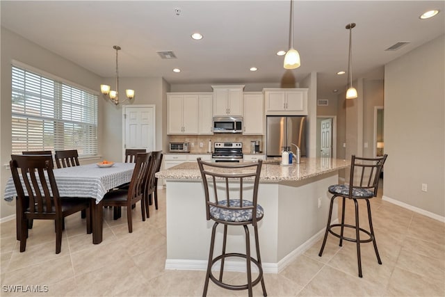 kitchen featuring a kitchen island with sink, white cabinetry, and stainless steel appliances