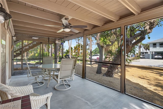 sunroom / solarium featuring beamed ceiling and ceiling fan