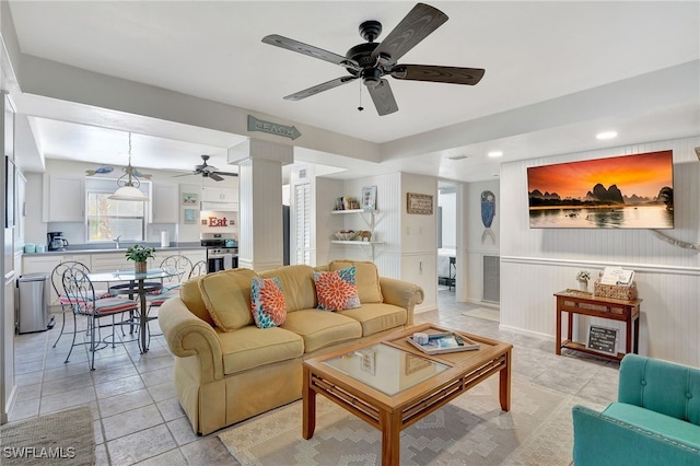 tiled living room featuring sink, decorative columns, and ceiling fan