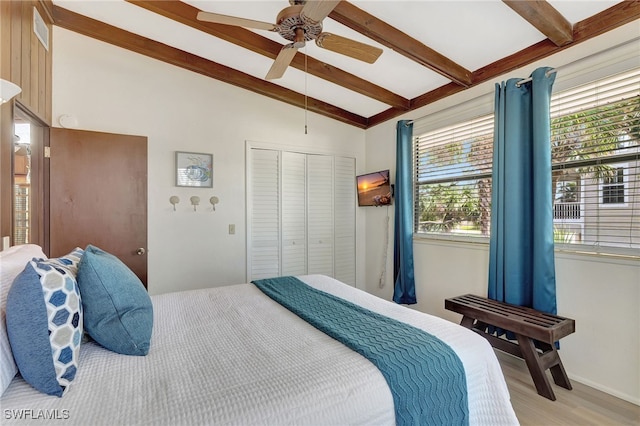 bedroom featuring ceiling fan, vaulted ceiling with beams, light wood-type flooring, and a closet