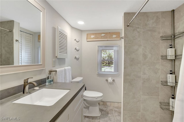 bathroom featuring tile patterned flooring, vanity, a tile shower, and toilet