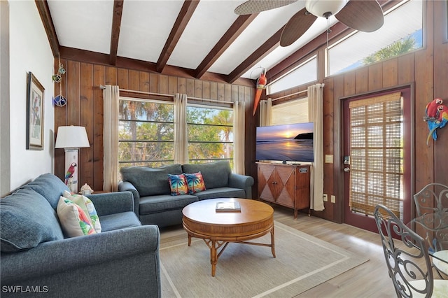 living room featuring plenty of natural light, wooden walls, and lofted ceiling with beams