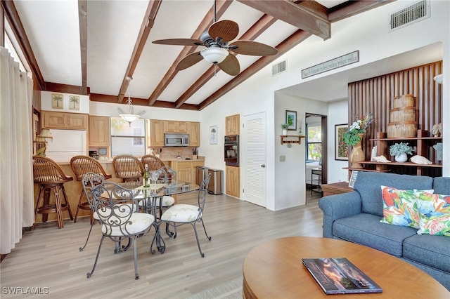 dining area featuring lofted ceiling with beams, ceiling fan, and light wood-type flooring