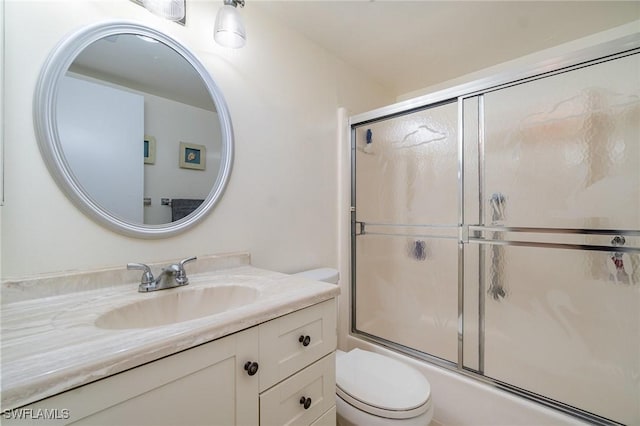 full bathroom featuring vanity, bath / shower combo with glass door, and toilet