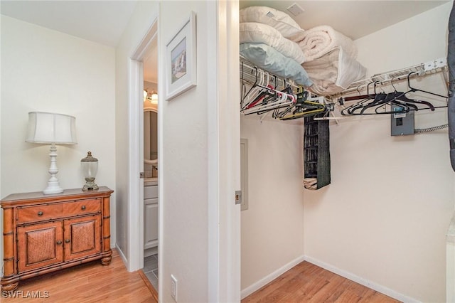 walk in closet with light hardwood / wood-style flooring