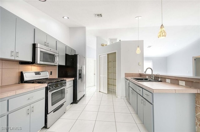 kitchen featuring pendant lighting, stainless steel appliances, tasteful backsplash, visible vents, and a sink