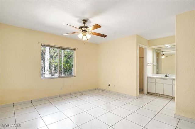 unfurnished bedroom with ceiling fan, a sink, a textured ceiling, and light tile patterned floors