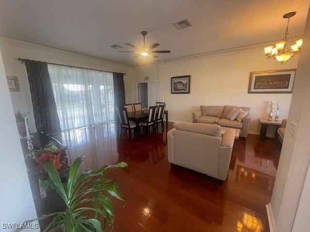 living room with crown molding, dark hardwood / wood-style floors, and ceiling fan with notable chandelier