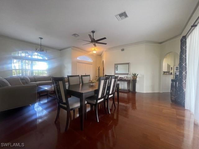 dining space featuring ornamental molding, dark hardwood / wood-style flooring, and ceiling fan with notable chandelier