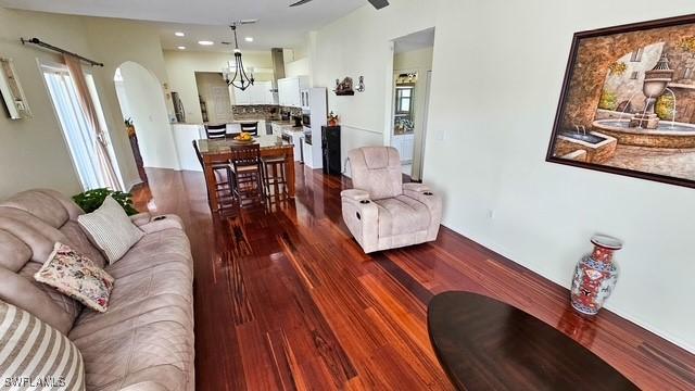 living room featuring an inviting chandelier, arched walkways, and wood finished floors