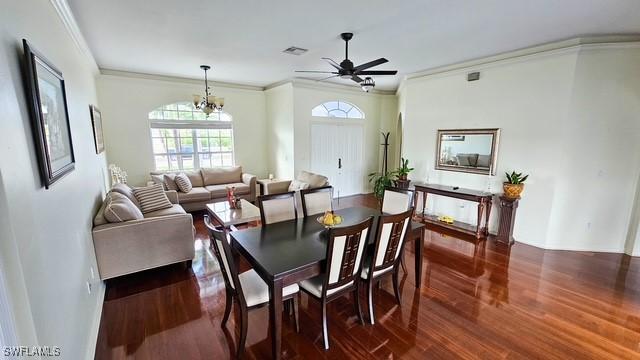 dining room with ceiling fan with notable chandelier, visible vents, dark wood-type flooring, and ornamental molding