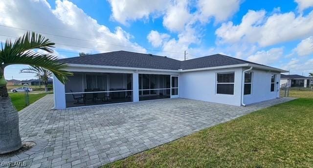 back of property featuring a lawn, a sunroom, and stucco siding