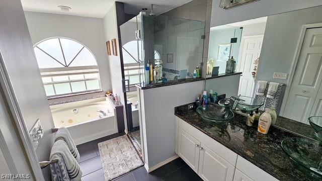 bathroom with double vanity, a tub with jets, a stall shower, and a sink