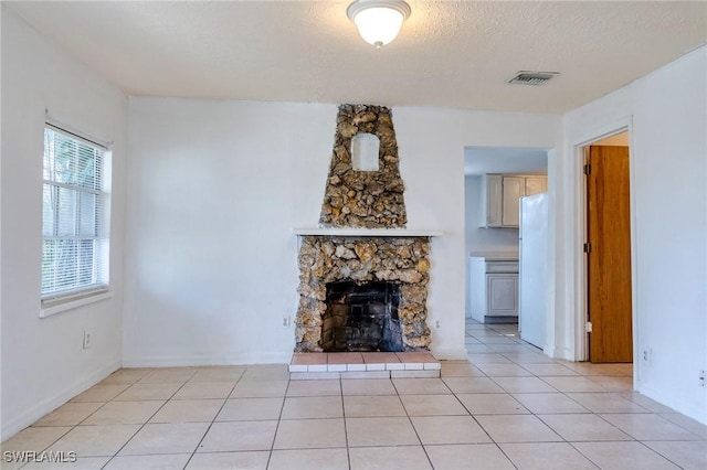 unfurnished living room with light tile patterned floors, a textured ceiling, and a fireplace