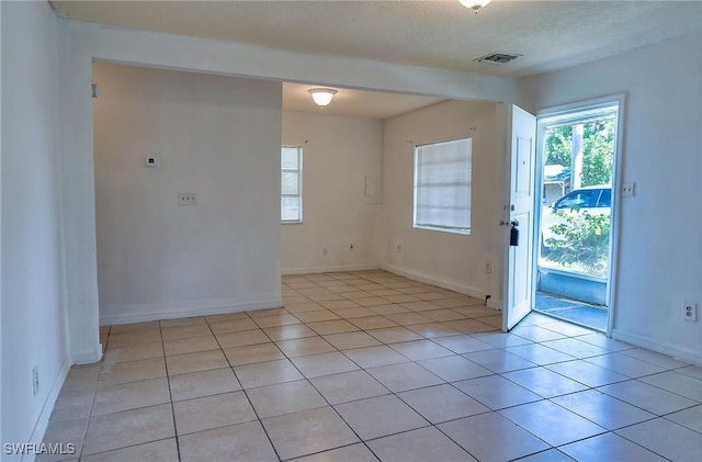 spare room featuring light tile patterned floors and a textured ceiling