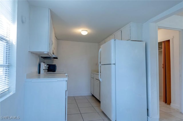 kitchen featuring white cabinetry, range, light tile patterned flooring, and white fridge