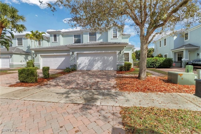 view of front of house featuring stucco siding, a tile roof, decorative driveway, and a garage