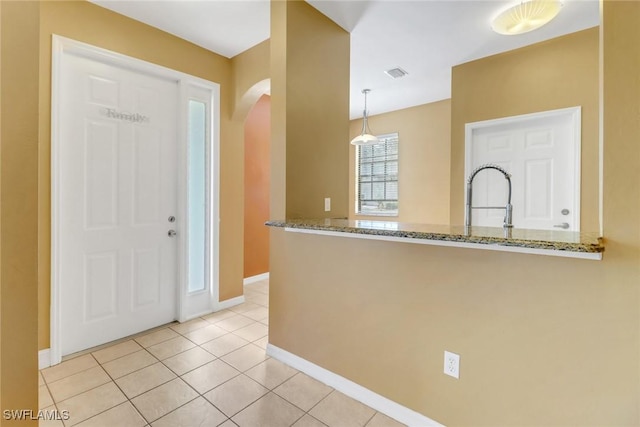 foyer entrance featuring arched walkways, visible vents, baseboards, and light tile patterned flooring