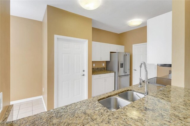 kitchen featuring light tile patterned flooring, white cabinetry, sink, high end refrigerator, and light stone countertops