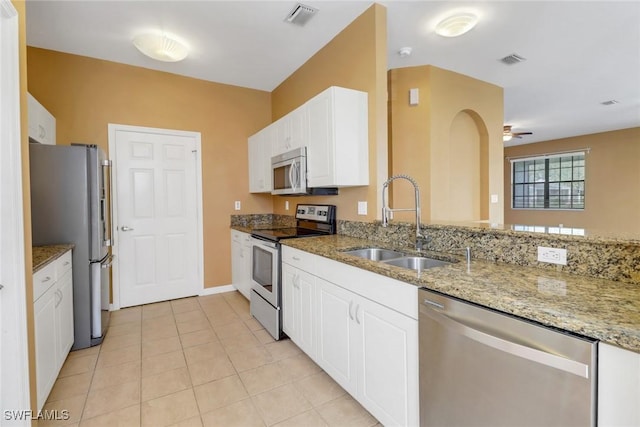 kitchen featuring sink, light tile patterned floors, white cabinetry, stainless steel appliances, and light stone counters