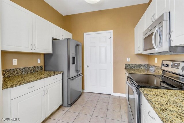 kitchen with white cabinetry, stainless steel appliances, light tile patterned floors, and dark stone counters