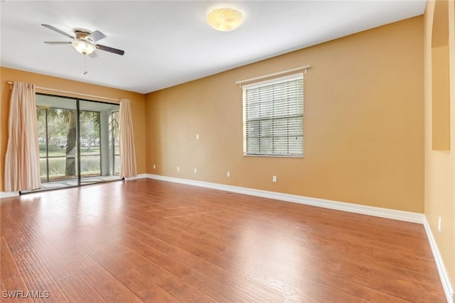 spare room with wood finished floors, a ceiling fan, and baseboards