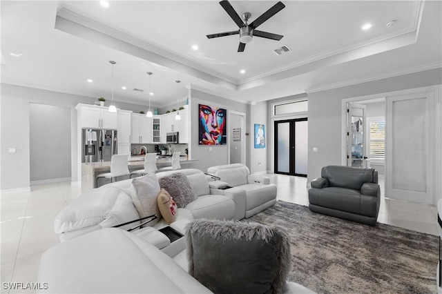 tiled living room with ornamental molding, ceiling fan, and a tray ceiling