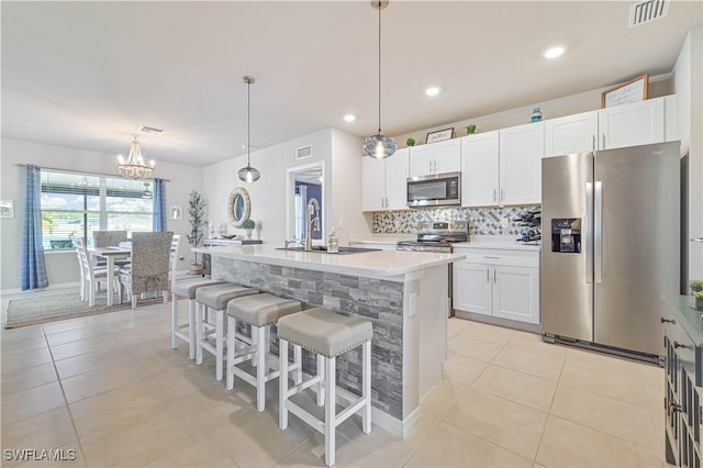 kitchen with appliances with stainless steel finishes, sink, a center island with sink, and white cabinets