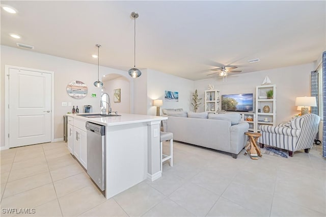 kitchen featuring decorative light fixtures, dishwasher, sink, white cabinets, and a center island with sink