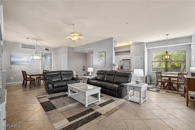 living room featuring ceiling fan with notable chandelier and light tile patterned floors