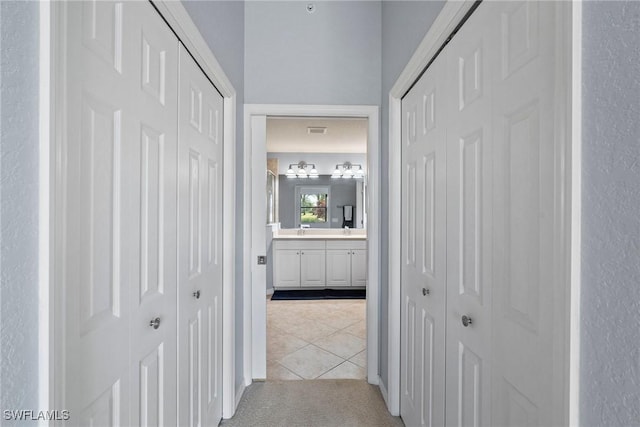 corridor with sink and light tile patterned floors