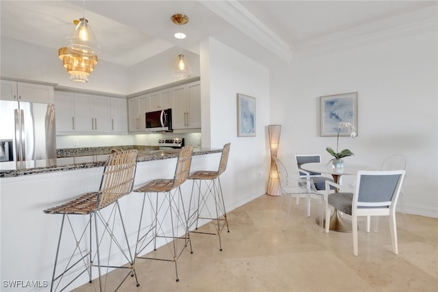 kitchen with stone counters, appliances with stainless steel finishes, a kitchen bar, hanging light fixtures, and kitchen peninsula