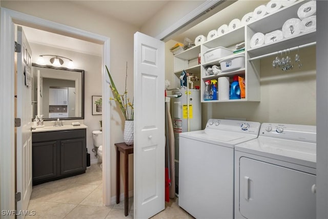 washroom featuring electric water heater, sink, washer and dryer, and light tile patterned floors