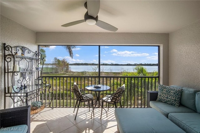 sunroom with ceiling fan and a water view